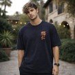 Male model wearing a black Jujutsu Kaisen oversized anime t-shirt with minimalist front artwork and casual oversized styling