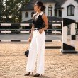 Side profile of black ribbed sleeveless polo knit top for women featuring a white contrast collar