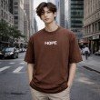Men's brown oversized 100% cotton crew neck T-shirt with minimal chest text print and relaxed streetwear fit.