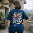 Female model showcasing the back graphic of a navy blue anime t-shirt featuring an action-inspired Luffy character print