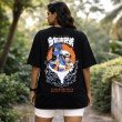 Female model wearing unisex black oversized Naruto Itachi Sasuke anime graphic cotton T-shirt front view.