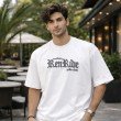 Male model wearing a white oversized anime graphic t-shirt with front text print and casual oversized styling.