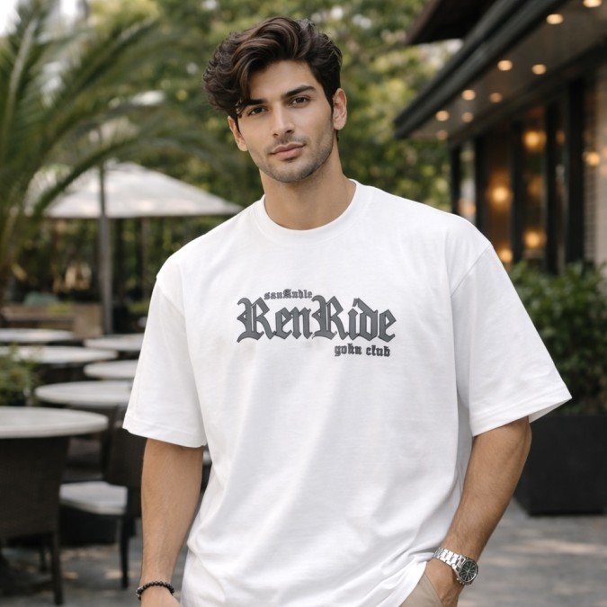 Male model wearing a white oversized anime graphic t-shirt with front text print and casual oversized styling.